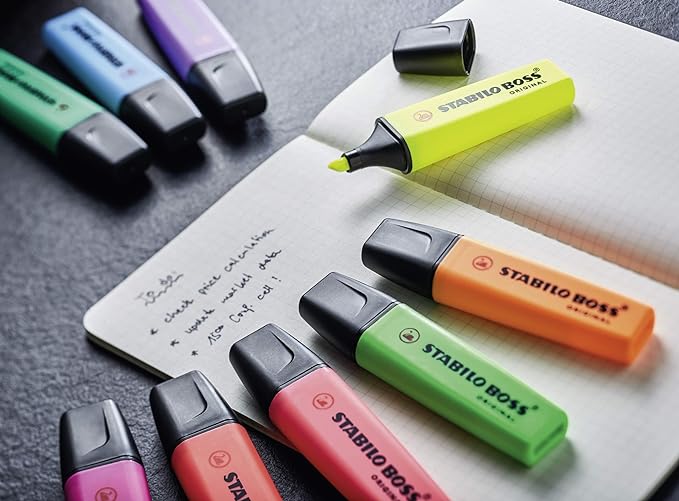 9 Multi colour Stabilo Boss highlighters and copy on a desk.